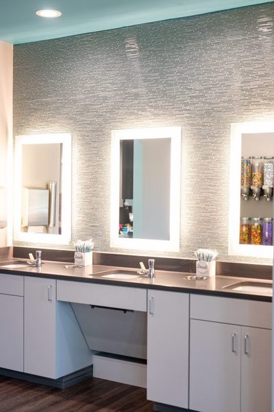 Brushing station with lit mirrors and toothbrush cups