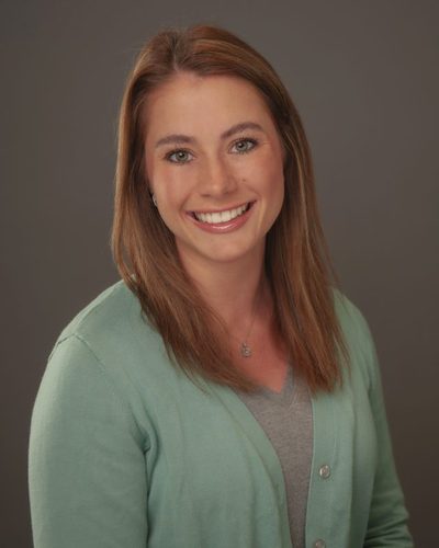Caroline Abbott smiling, wearing a green cardigan