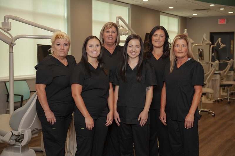 Members of the Central Missouri Orthodontics clinical team standing together in a treatment bay