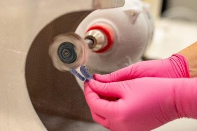 Gloved hands polishing a retainer piece in our office